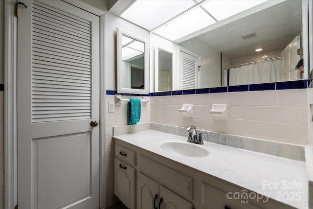 bathroom featuring tile walls, tasteful backsplash, vanity, and curtained shower