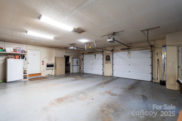 garage with white fridge, a garage door opener, and heating unit