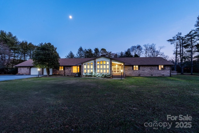 view of front of property featuring crawl space, roof with shingles, a front lawn, brick siding, and a garage