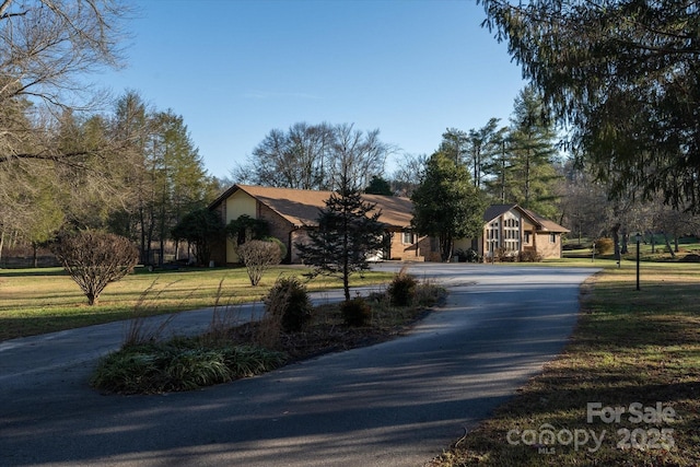view of front of home with a front yard and curved driveway
