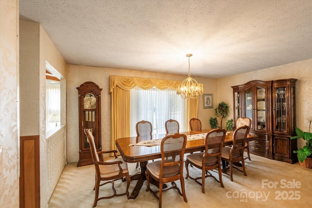 dining space featuring light colored carpet, an inviting chandelier, and a textured ceiling