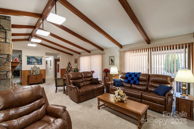 living room featuring a fireplace, a wainscoted wall, light carpet, and lofted ceiling with beams