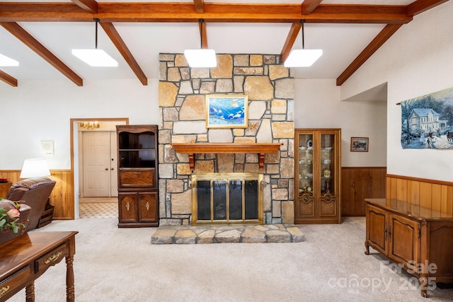 carpeted living room featuring wood walls, a fireplace, vaulted ceiling with beams, and a wainscoted wall