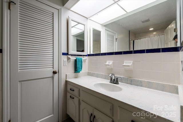 full bathroom featuring vanity, backsplash, and visible vents