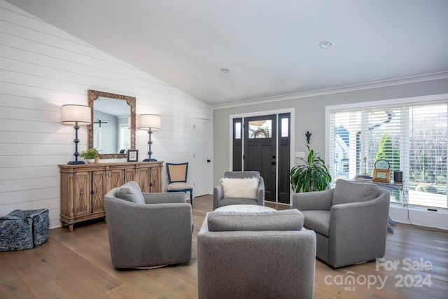 living room with wood walls, wood-type flooring, and lofted ceiling