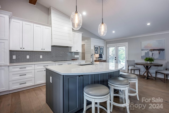 kitchen with white cabinets, hanging light fixtures, lofted ceiling, and sink