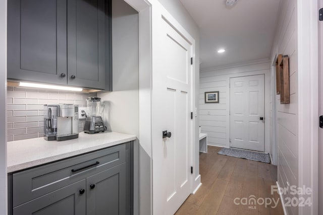 bar featuring backsplash, light hardwood / wood-style floors, and gray cabinetry