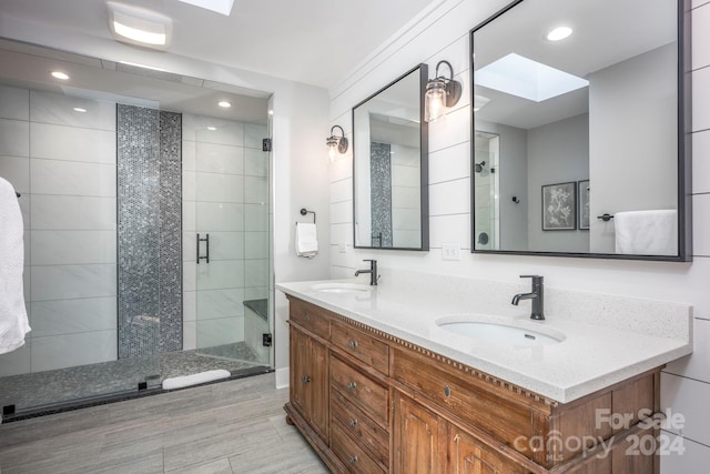 bathroom featuring a skylight, a shower with door, and vanity