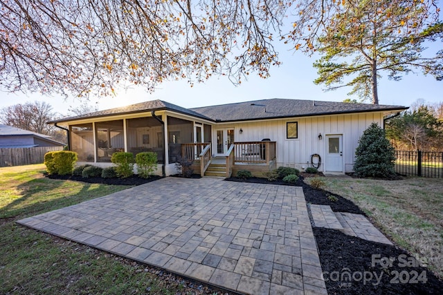 rear view of house featuring a yard, a patio, and a sunroom