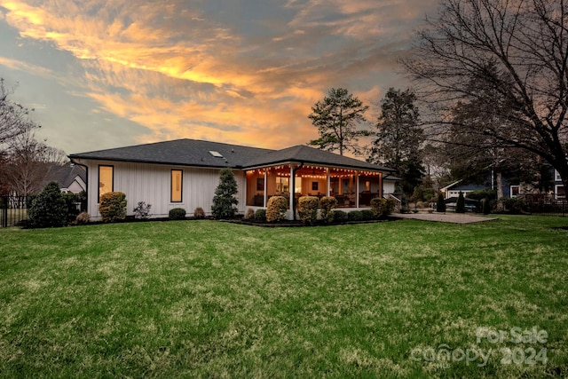 back house at dusk with a yard and a patio