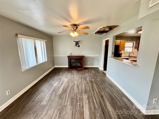 unfurnished living room with ceiling fan, sink, and dark wood-type flooring