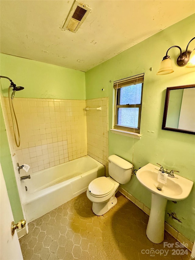 bathroom with tile patterned flooring, toilet, and tiled shower / bath