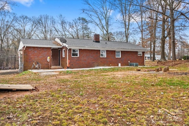 rear view of house with central air condition unit and a yard