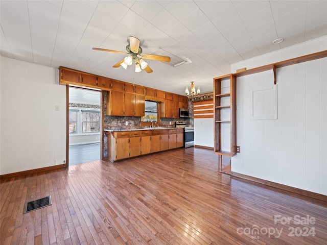 kitchen featuring sink, wood-type flooring, decorative backsplash, ceiling fan with notable chandelier, and appliances with stainless steel finishes