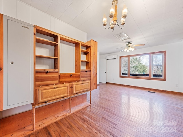 living room featuring a wall mounted AC, wood-type flooring, and ceiling fan with notable chandelier