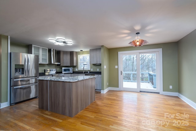 kitchen featuring stainless steel appliances, a kitchen island, light hardwood / wood-style floors, and wall chimney exhaust hood