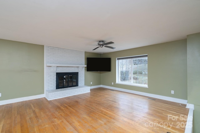 unfurnished living room featuring hardwood / wood-style flooring, ceiling fan, and a fireplace