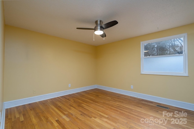 empty room with ceiling fan, a textured ceiling, and light wood-type flooring