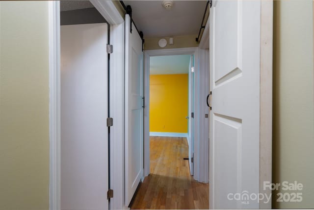 hall featuring wood-type flooring and a barn door