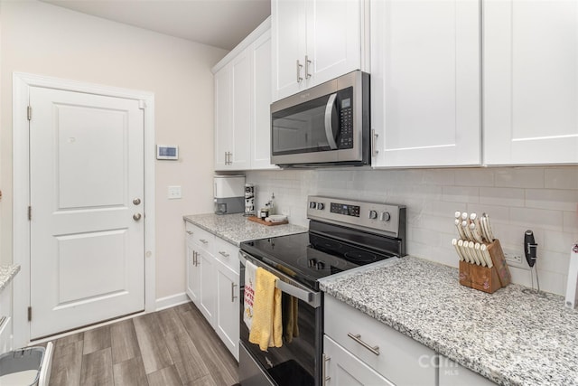 kitchen with backsplash, light stone counters, white cabinets, and appliances with stainless steel finishes