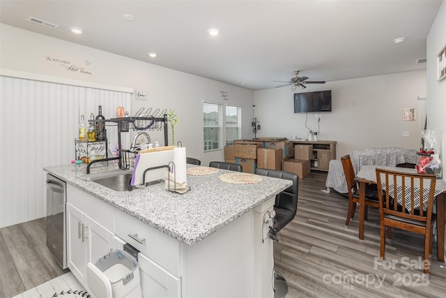 kitchen with white cabinetry, sink, ceiling fan, stainless steel dishwasher, and a kitchen island with sink