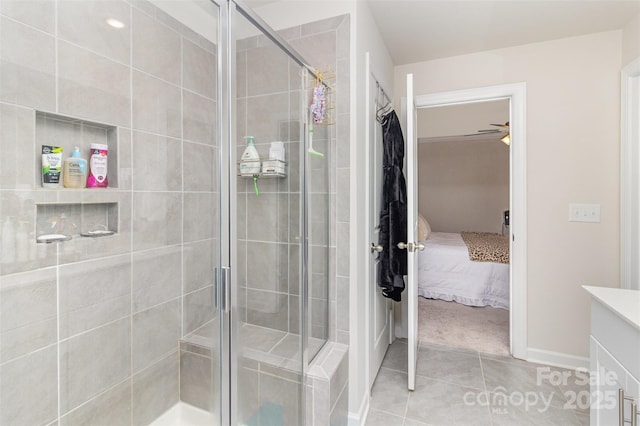 bathroom with tile patterned floors, ceiling fan, a shower with door, and vanity