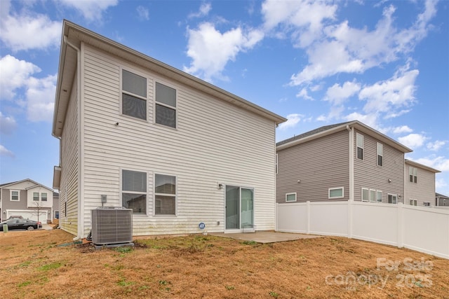 back of property with central air condition unit, a lawn, and a patio