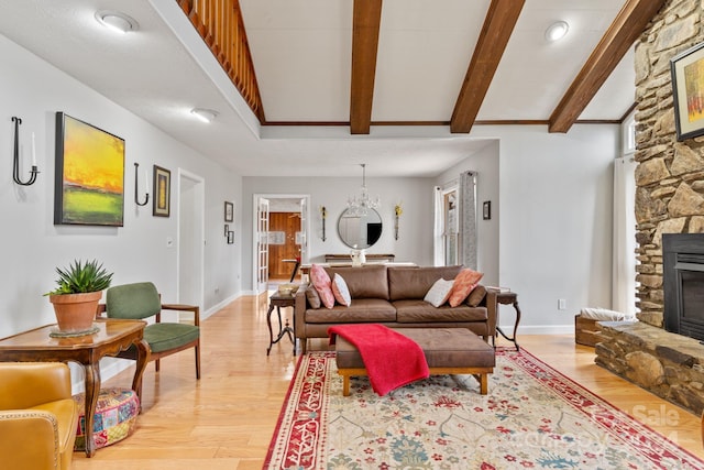 living room featuring vaulted ceiling with beams, light hardwood / wood-style flooring, and a stone fireplace