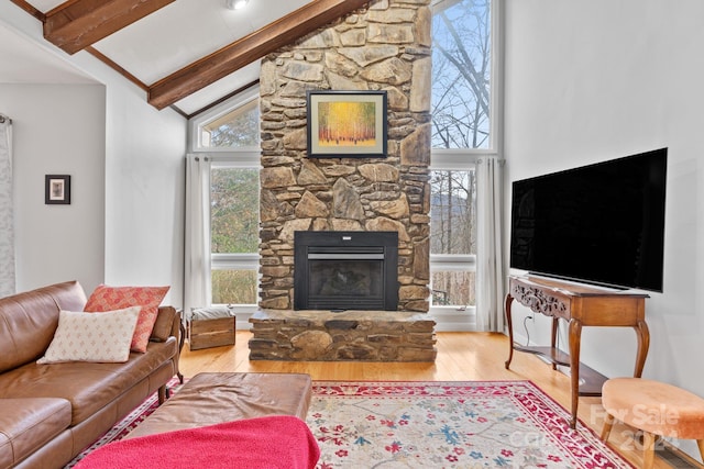 living room with a fireplace, beam ceiling, a wealth of natural light, and wood-type flooring