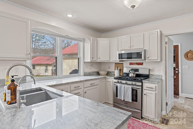 kitchen with white cabinets, sink, light tile patterned floors, appliances with stainless steel finishes, and light stone counters