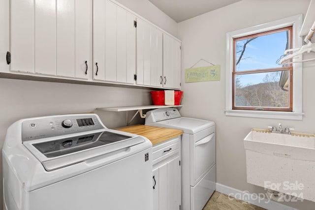 laundry area with cabinets, washing machine and dryer, and sink