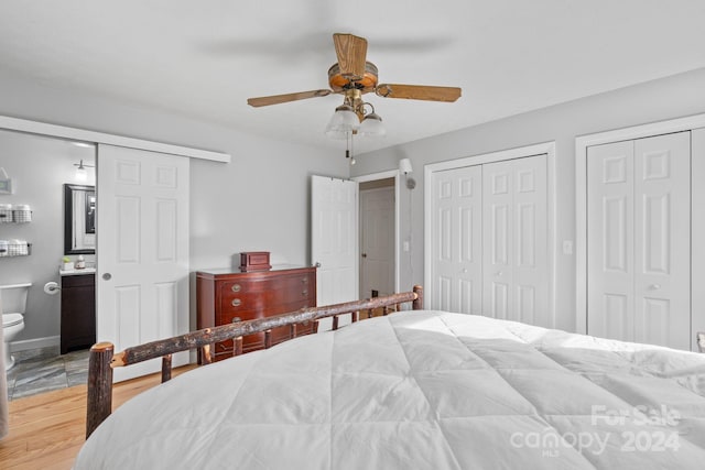 bedroom featuring multiple closets, ceiling fan, ensuite bathroom, and light hardwood / wood-style floors