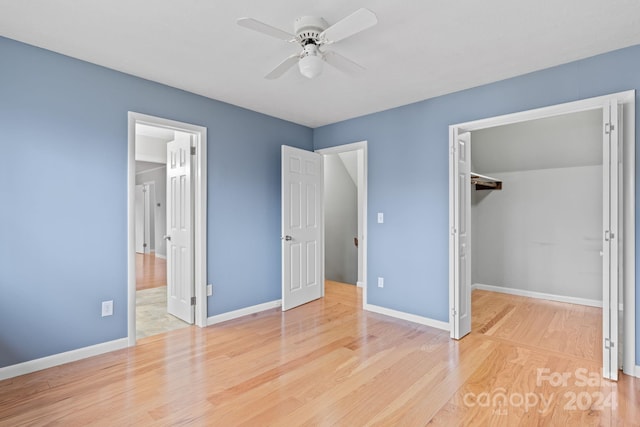 unfurnished bedroom featuring ceiling fan, a closet, a spacious closet, and light hardwood / wood-style floors