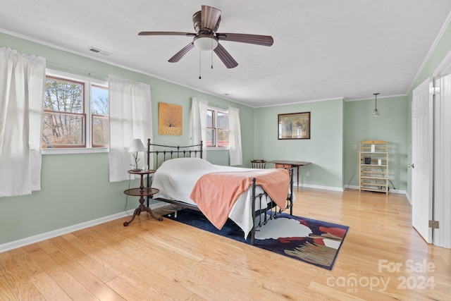 bedroom featuring ceiling fan, multiple windows, crown molding, and light hardwood / wood-style flooring