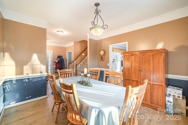 dining room featuring light wood-type flooring and crown molding