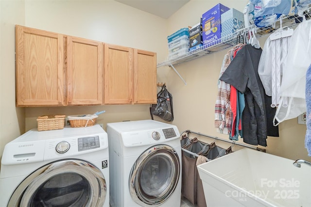 clothes washing area featuring sink, cabinets, and washer and clothes dryer