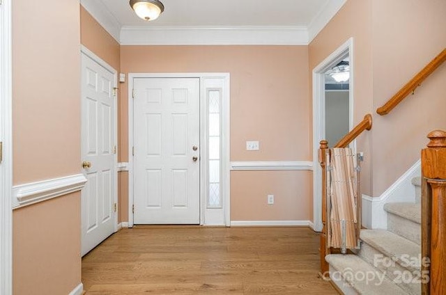 entrance foyer with stairs, ornamental molding, baseboards, and light wood-style floors