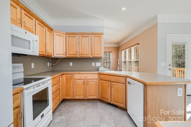 kitchen featuring a peninsula, white appliances, ornamental molding, and a sink