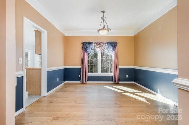 unfurnished dining area with crown molding, baseboards, and wood finished floors