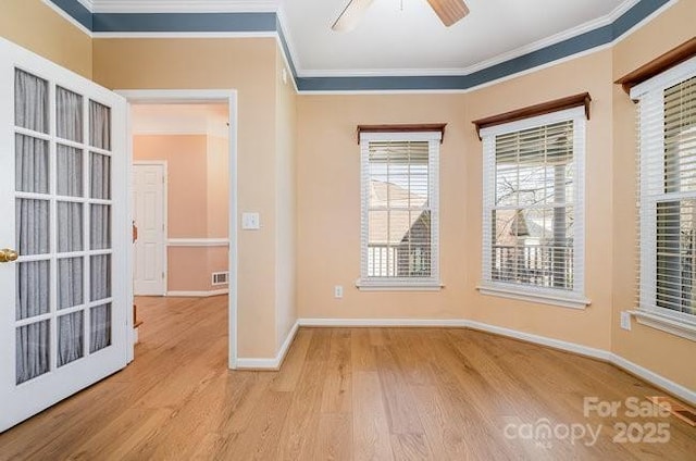 empty room featuring ornamental molding, wood finished floors, a ceiling fan, and baseboards