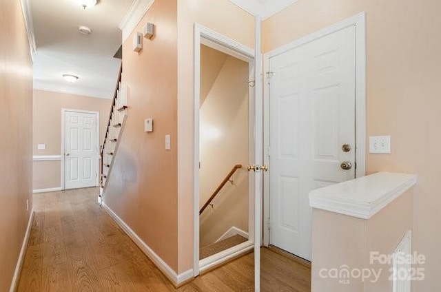 hall featuring baseboards, light wood finished floors, and stairs