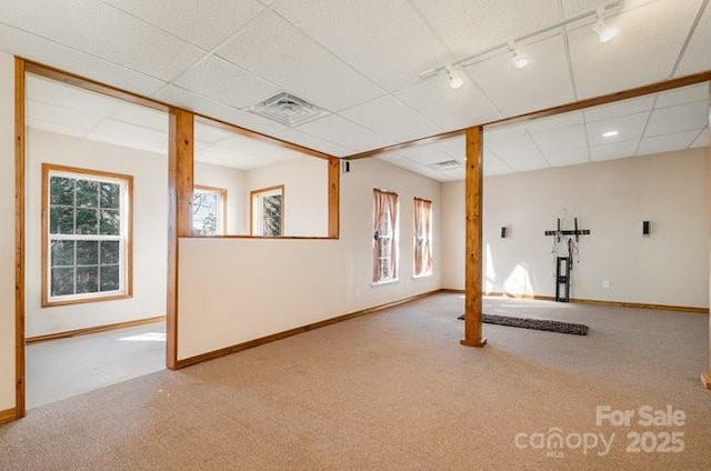 interior space featuring baseboards, visible vents, carpet, a paneled ceiling, and track lighting