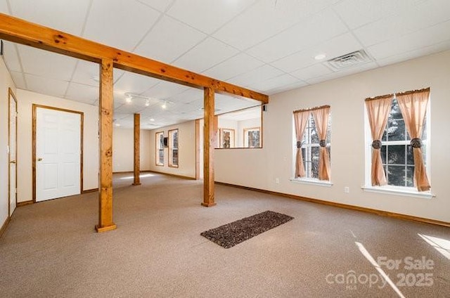 basement featuring carpet floors, baseboards, visible vents, and a paneled ceiling