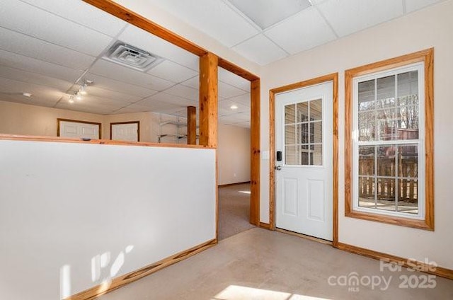 doorway with a paneled ceiling, visible vents, and baseboards