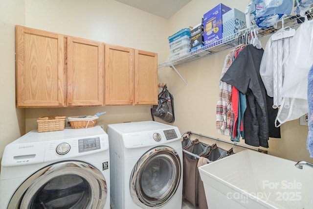 washroom with washer and dryer, cabinet space, and a sink