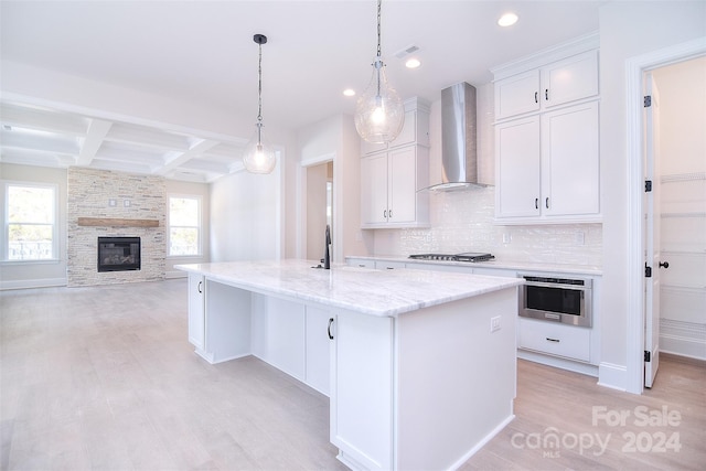 kitchen featuring wall chimney exhaust hood, coffered ceiling, a kitchen island with sink, beam ceiling, and white cabinets