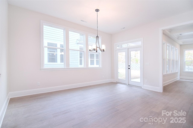 spare room with light wood finished floors, visible vents, baseboards, an inviting chandelier, and french doors