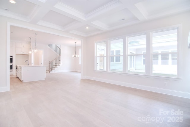 unfurnished living room with plenty of natural light, beam ceiling, a chandelier, and a sink