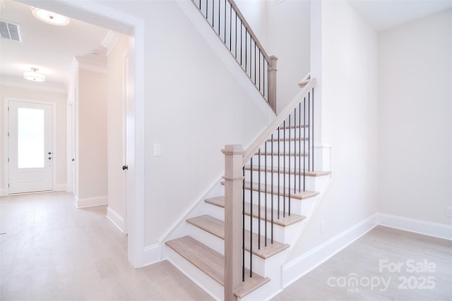 stairway featuring baseboards, visible vents, wood finished floors, and ornamental molding