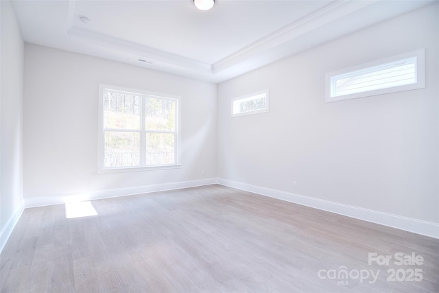 unfurnished room featuring light wood-type flooring, baseboards, and a tray ceiling